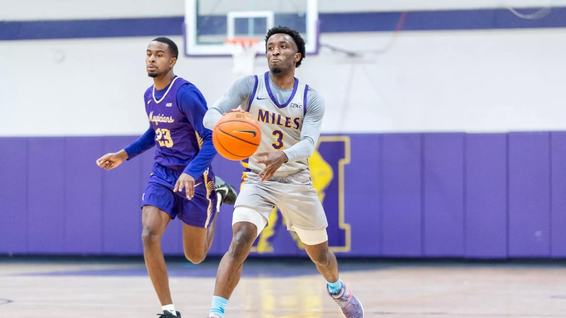 A Miles guard controls the ball in his home white jersey.